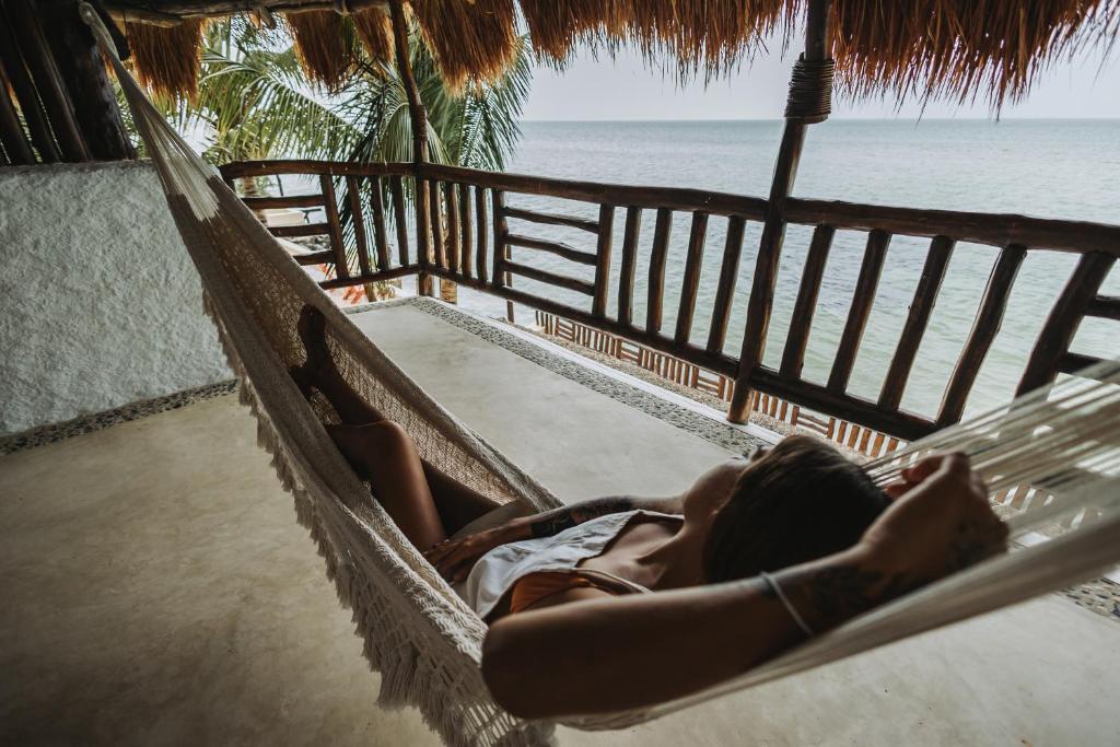 A woman laying in a hammock on a balcony overlooking the ocean.