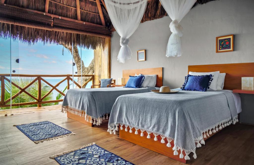 Two beds in a room with a view of the ocean.