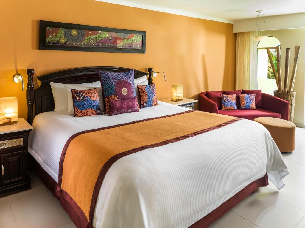 A bedroom with orange walls and a large bed.