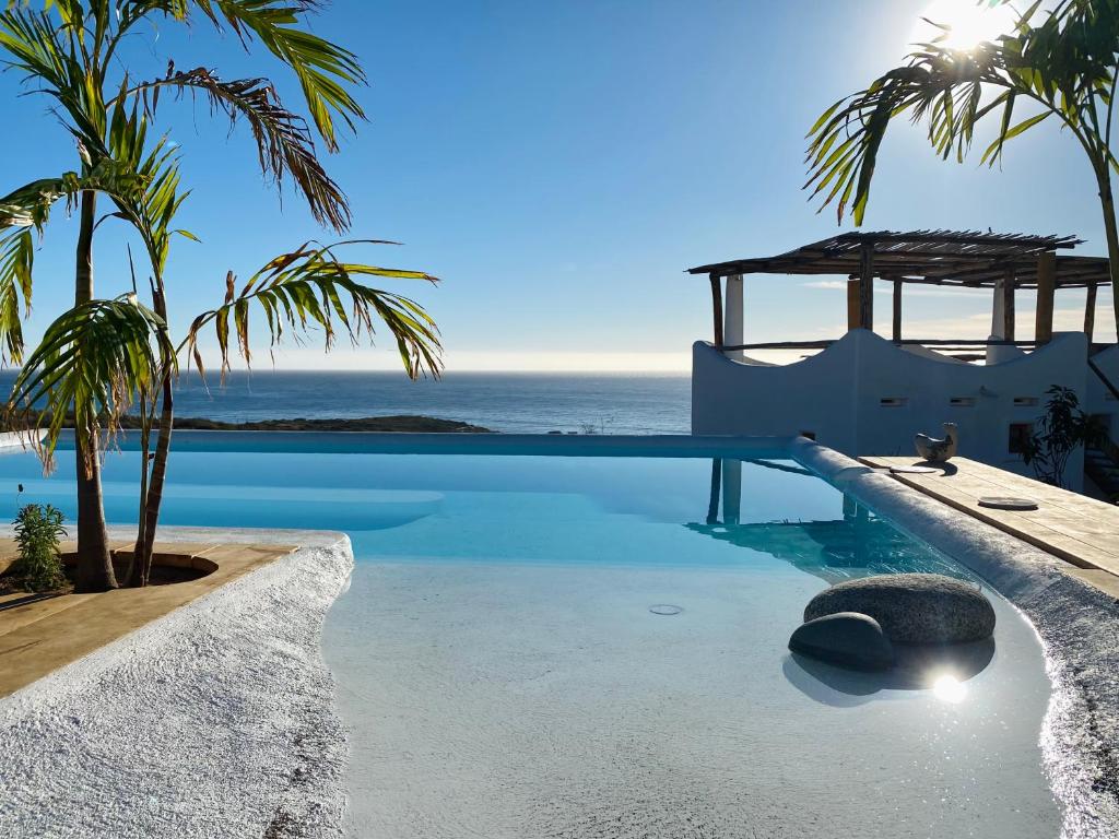 A pool with palm trees and a view of the ocean.