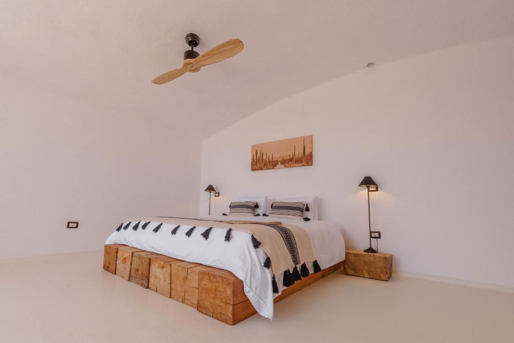 A white bedroom with wooden floors and a ceiling fan.