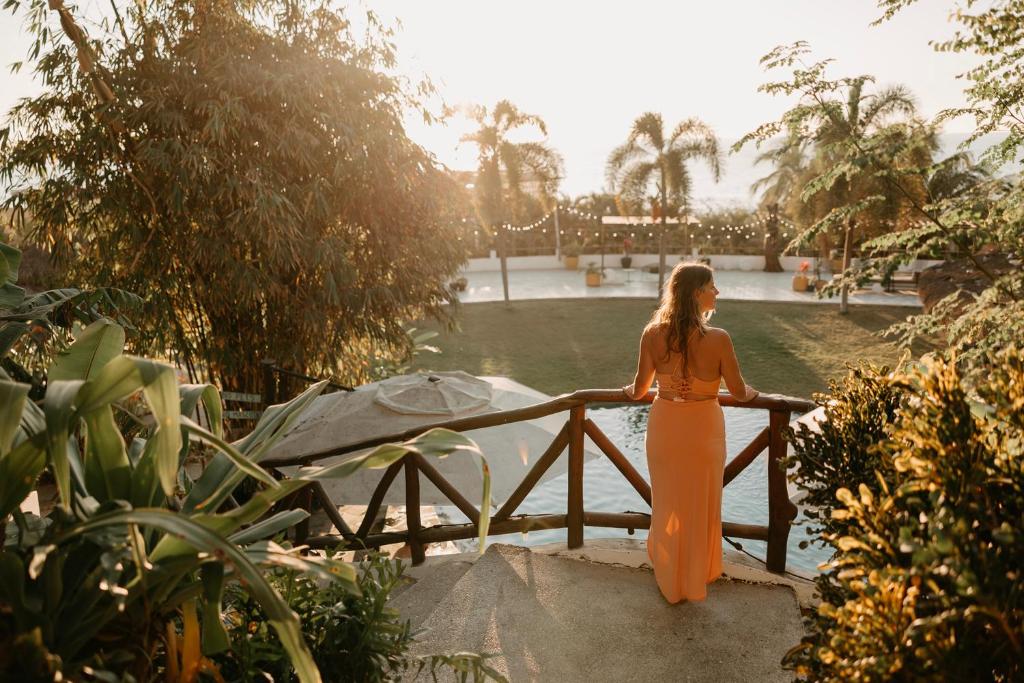 A woman in an orange dress standing next to a pool.