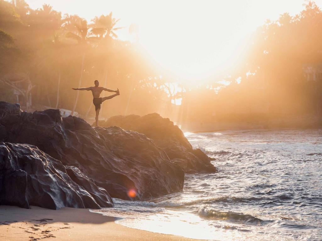 A woman doing yoga on the beach at sunset.
