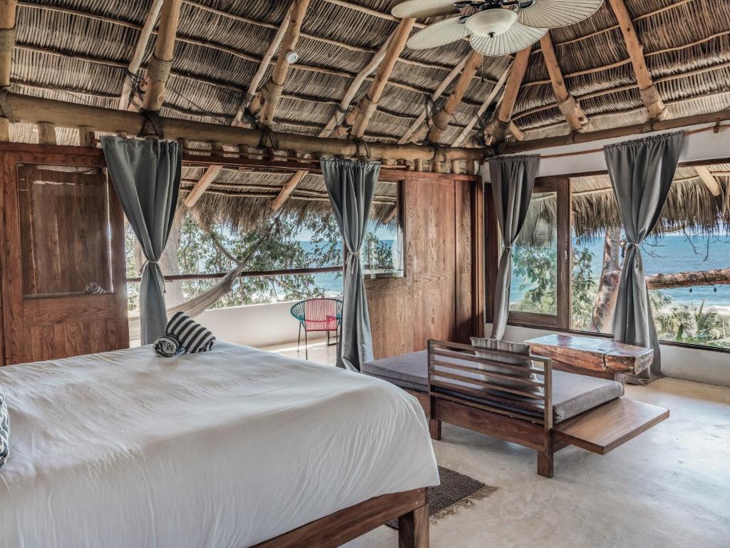 A bedroom with a thatched roof and a view of the ocean.