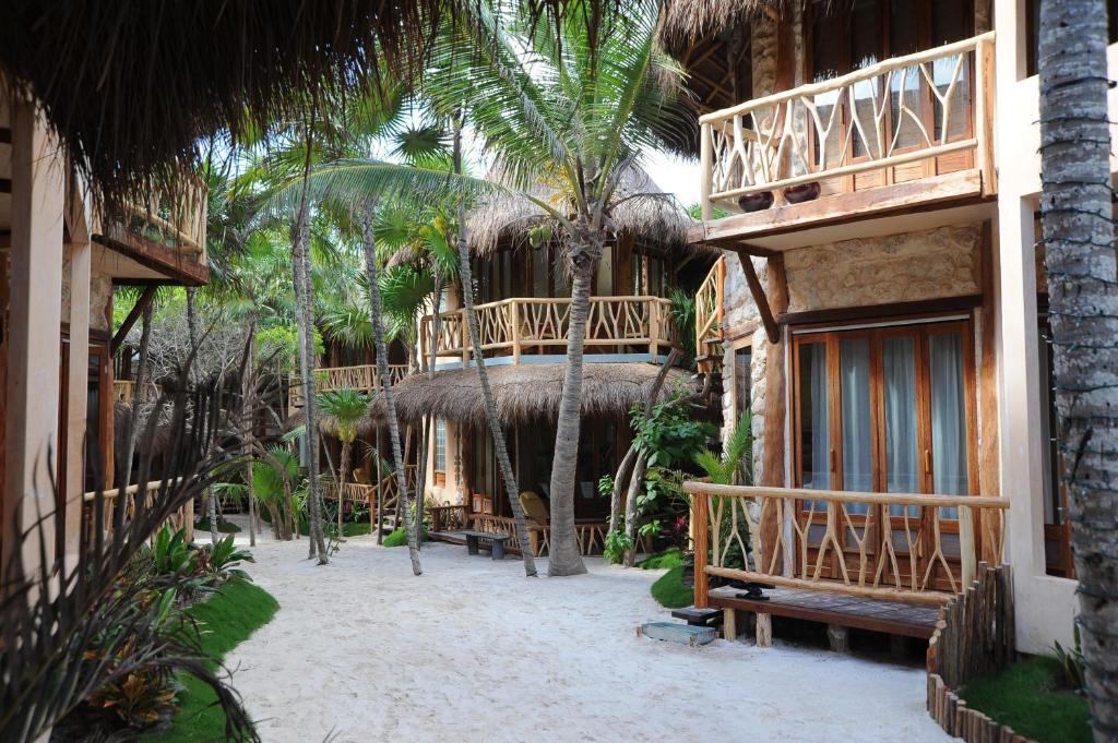 A pathway leading to a beach house with thatched roofs.