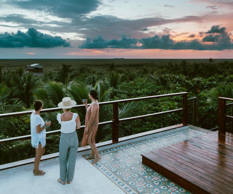 Three women standing on a balcony overlooking the ocean.